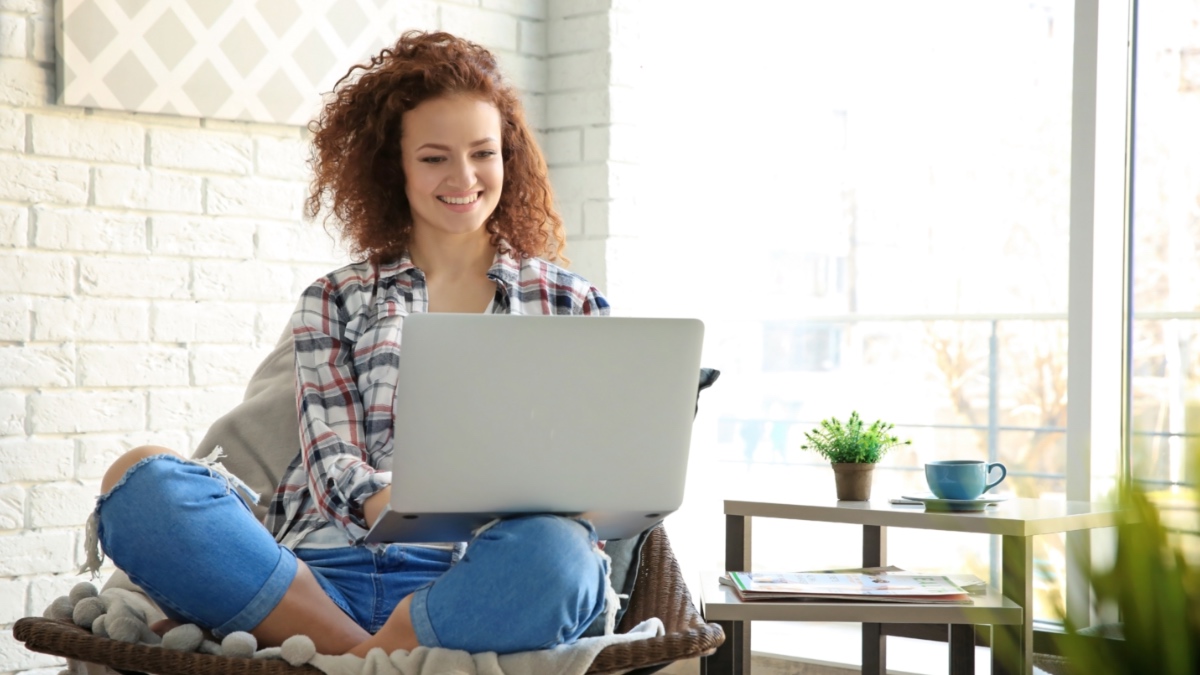 Eine junge Frau, die auf ihren Laptop schaut.