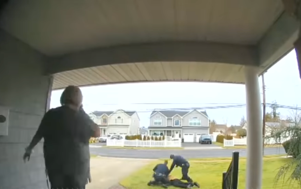 Eine Sicherheitskamera filmt einen Mann, der von Polizisten festgenommen wird.