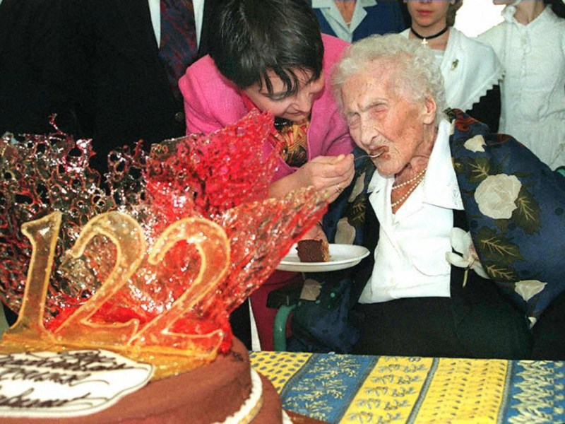 Eine alte Frau feiert ihren 122. Geburtstag und wird mit Torte gefüttert.