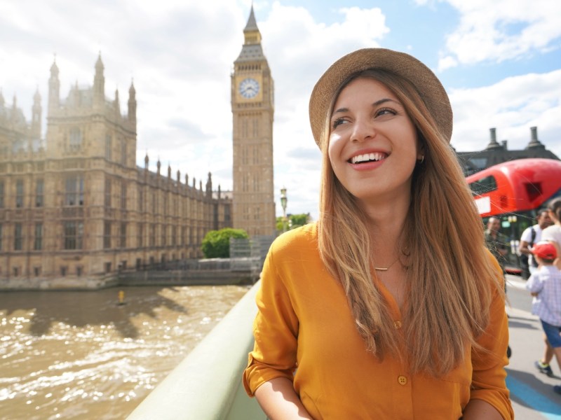 Eine lächelnde junge Touristin in London posiert vor Big Ben.