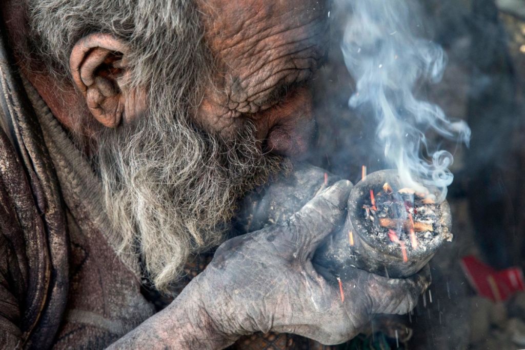 Ein alter Mann mit schmutzigem Gesicht raucht eine Pfeife.