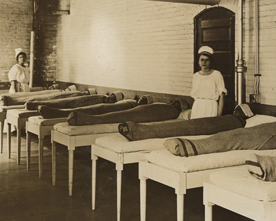 Ein Schwarzweiß-Foto von eingeschnürten Patienten in einer psychiatrischen Klinik, ca. 1900.