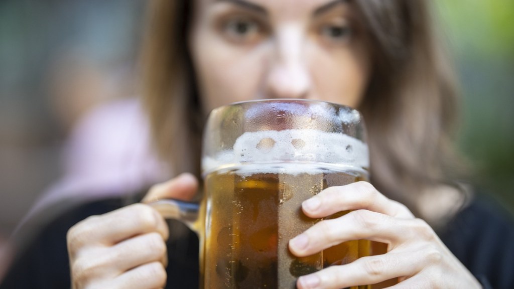 Eine Frau hält ein großes Bier in der Hand.