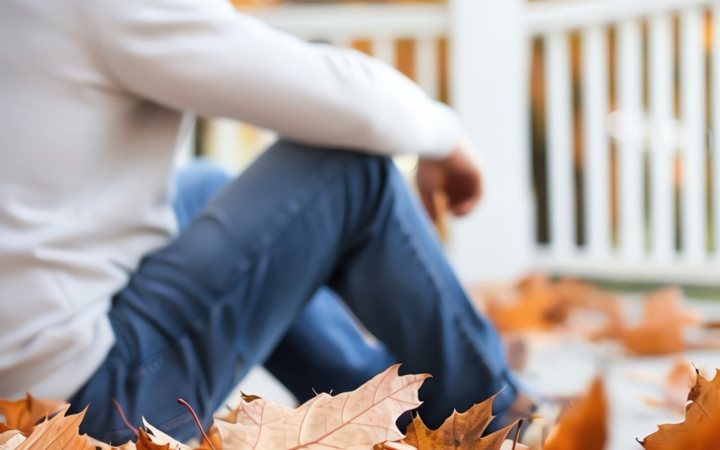 Ein Mann sitzt auf einer Veranda im Herbst.